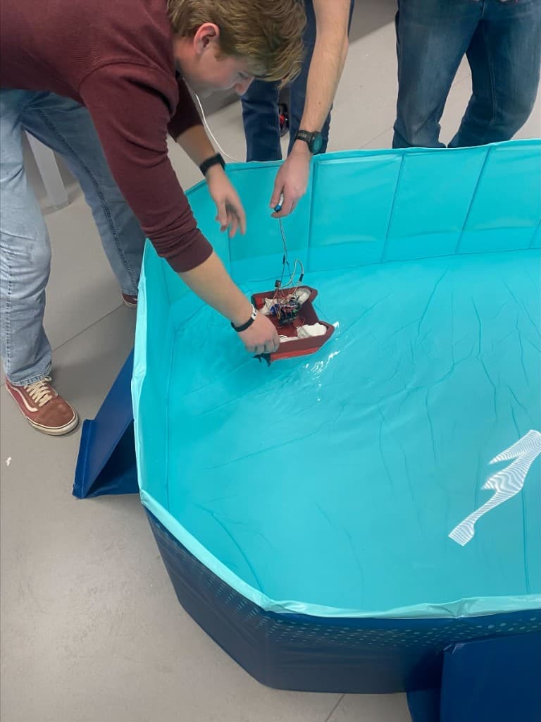 Team lowering the vessel into a pool for buoyancy testing